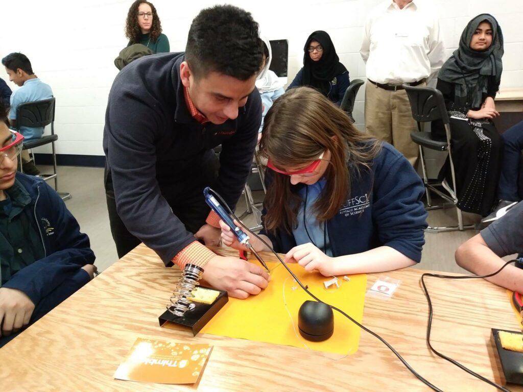 man helping girl learn how to solder